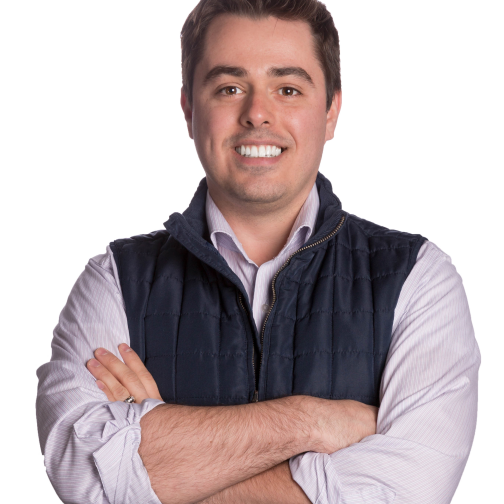 A man with dark hair smiling at the camera, wearing a blue vest over a white shirt, arms crossed, representing a property management business, isolated on a white background.