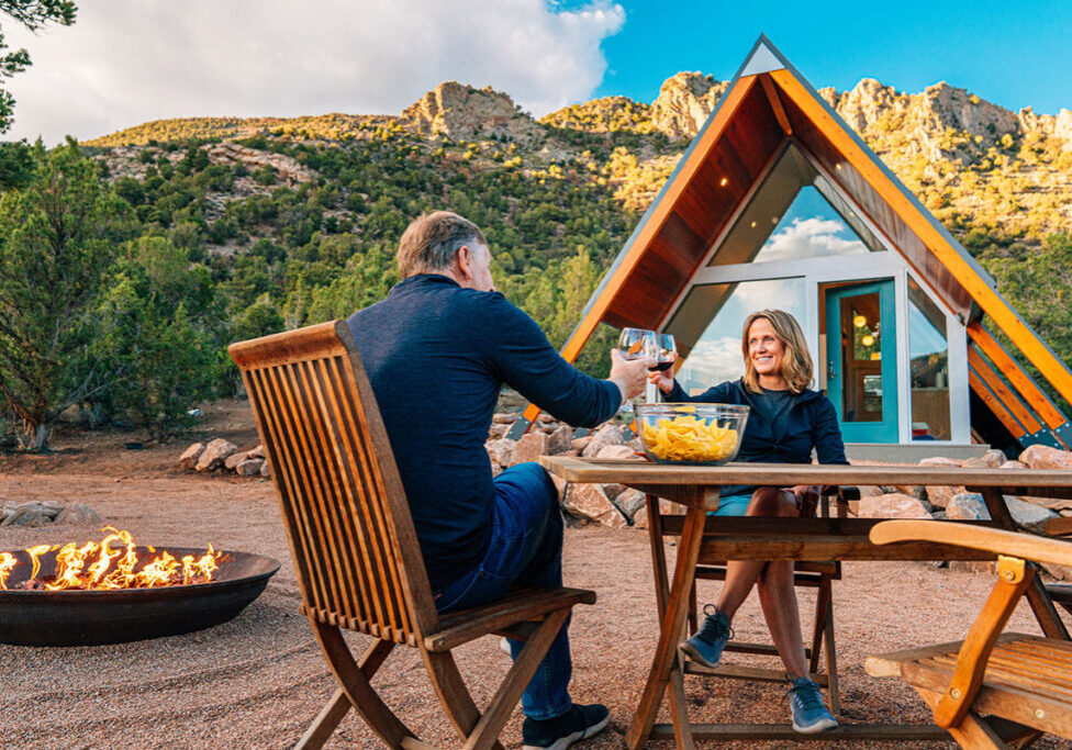 a couple sitting in front of the vacation rental property franchise tossing of a glass of wine