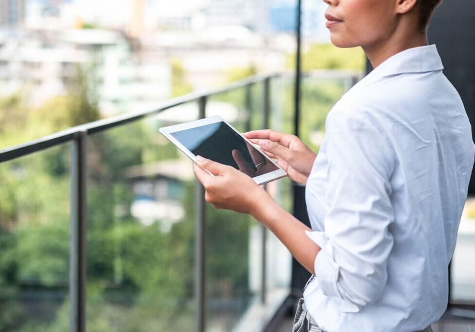 a woman holding a tablet on the balcony working on a property management business