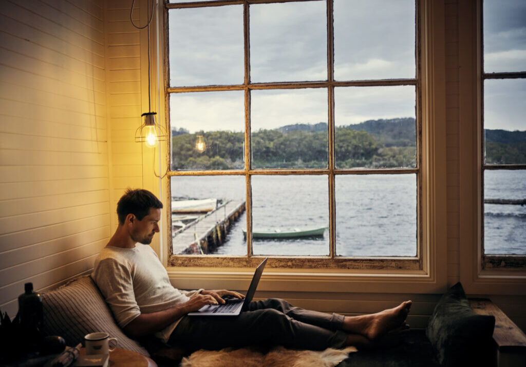 a man sitting next to the window while working on his laptop for a property management business