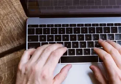 Hands typing on a laptop keyboard, perhaps managing a vacation rental franchise.